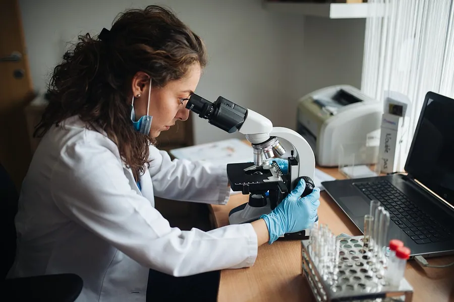 Lab technician looking through the microscope. Фото: Shixart1985 / CC BY 2.0, via Wikimedia Commons
