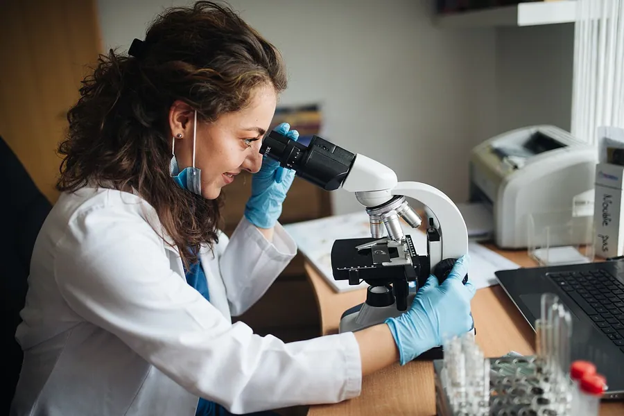 Lab technitian looking through the microscope while adjusting coarse knob. Фото: Shixart1985 / CC BY 2.0, via…