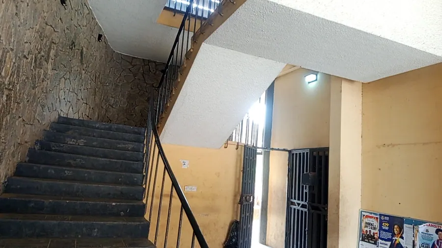 Daytime indoor photo capturing flights of stairs with black railings, textured stone accent walls, a metal…