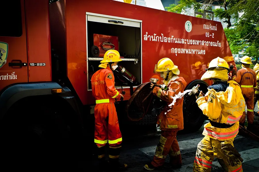 Firefighters prepare to extinguish a pile of flaming tires at the Red Shirt barricade near Chulalongkorn…