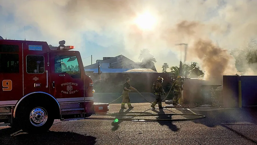 Firefighters walking from fire engine toward dumpster fire. Фото: KatieHinde / CC BY-SA 4.0, via Wikimedia…