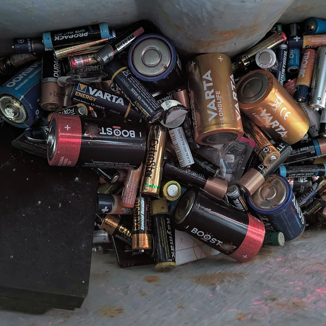 Photograph of the inside of a battery recycling container showing a bunch of used electric batteries at the…