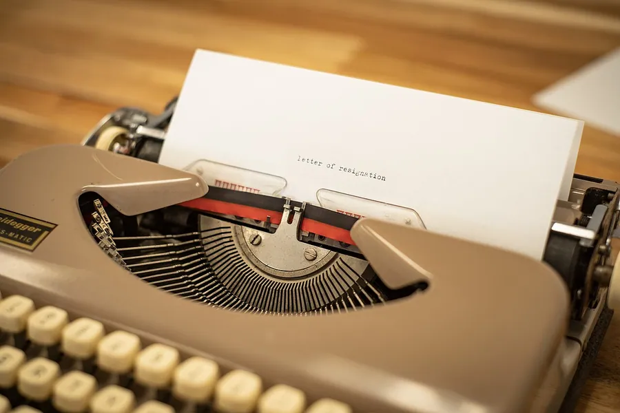 Photo of the start of a letter of resignation being typed out using an old typewriter. You can use this image…
